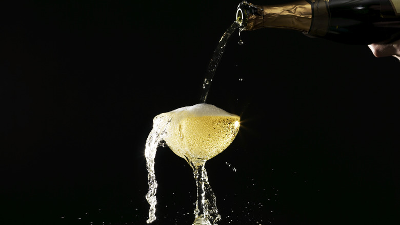 sparkling wine being poured into an overflowing coup glass