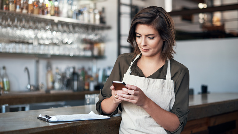 Hostess in apron on smartphone