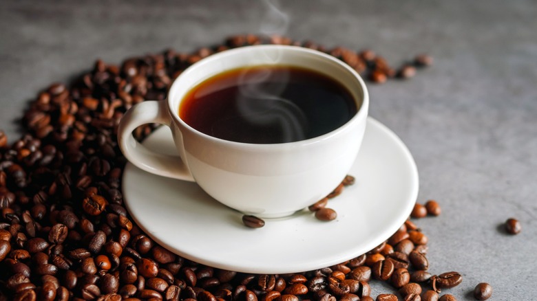 Cup of coffee surrounded by coffee beans