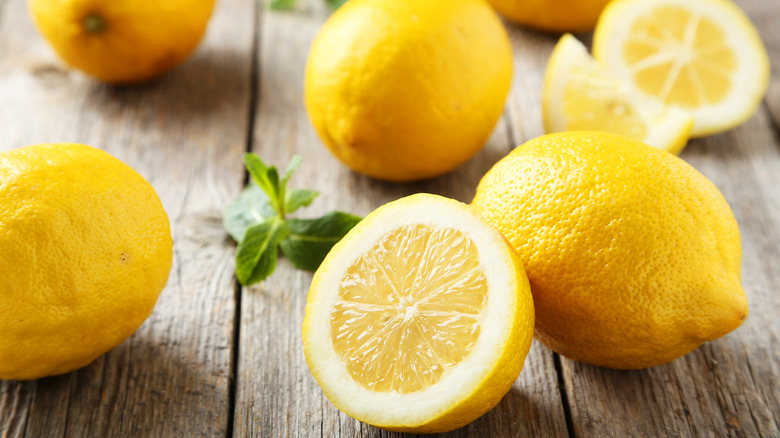 whole and cut lemons on wooden table