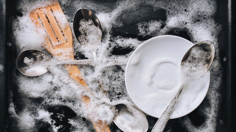 dishes soaking in soapy water in sink