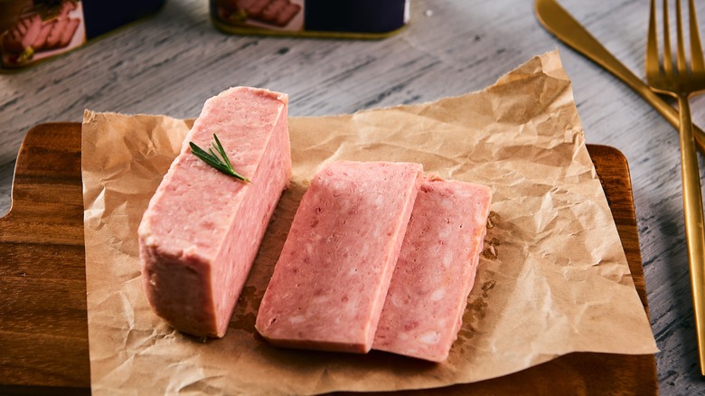 Sliced pink canned meat SPAM on butcher paper cutting board