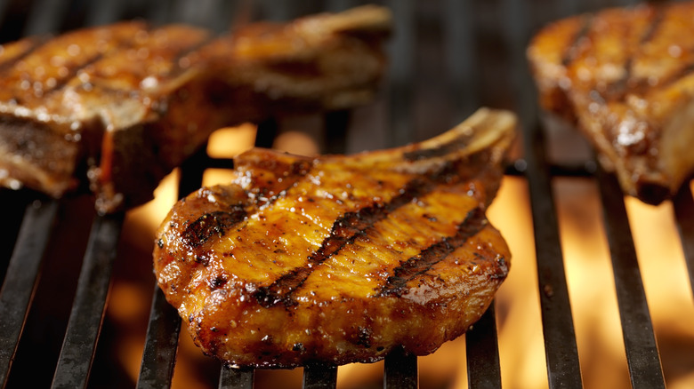 Three pork chops on a flaming grill