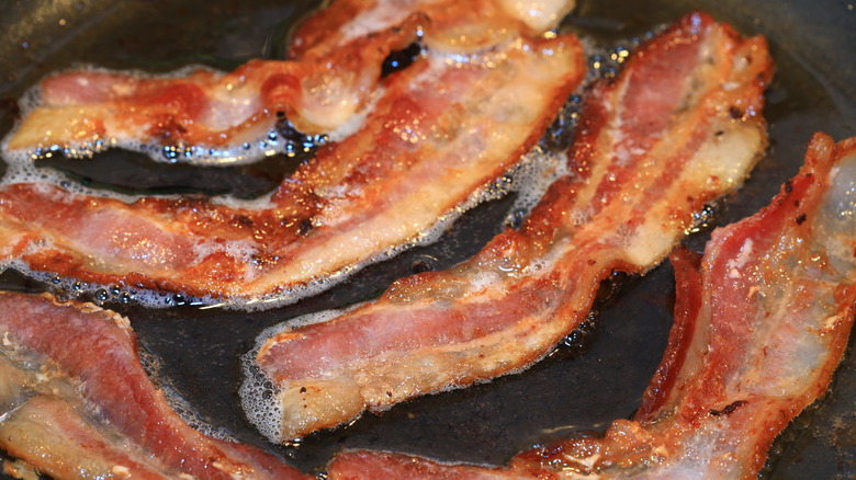 Bacon strips frying in a pan