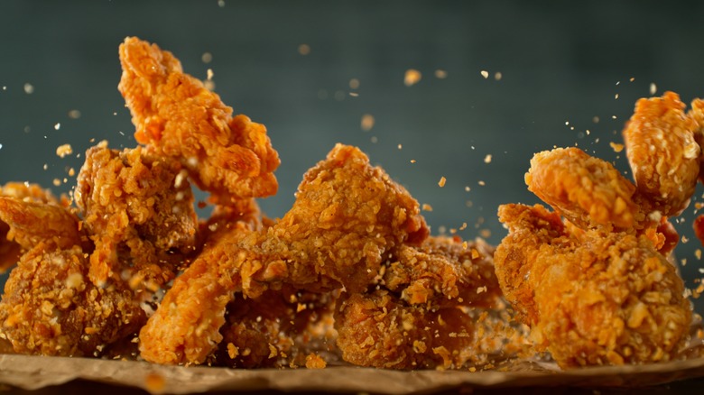 fried chicken being tossed on table
