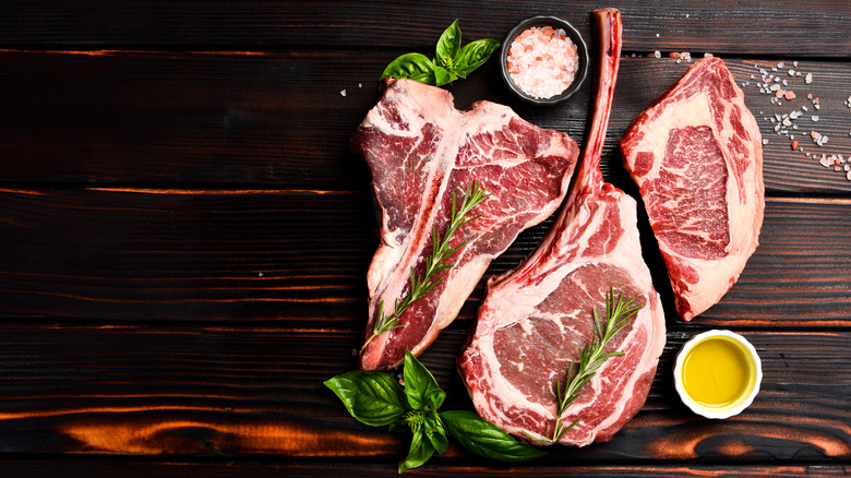 A t-bone, tomahawk, and ribeye steak with seasonings