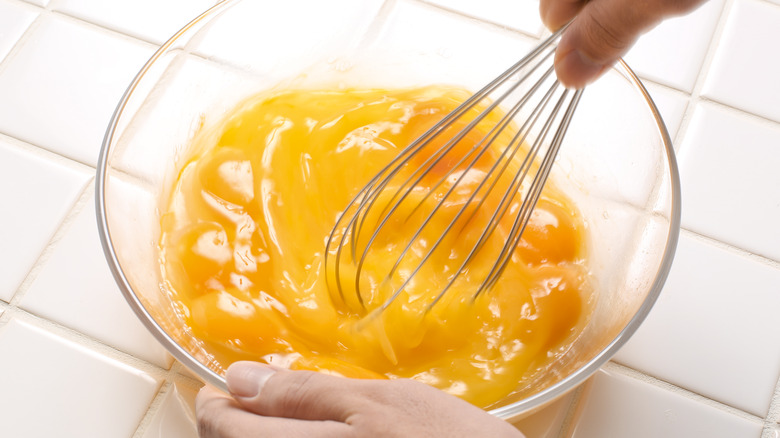 whisking eggs in a glass bowl