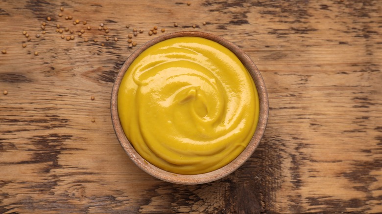 Yellow mustard in wooden bowl