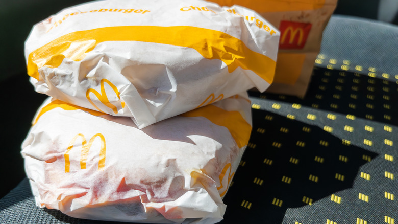 A person holds a McDonald's cheeseburger