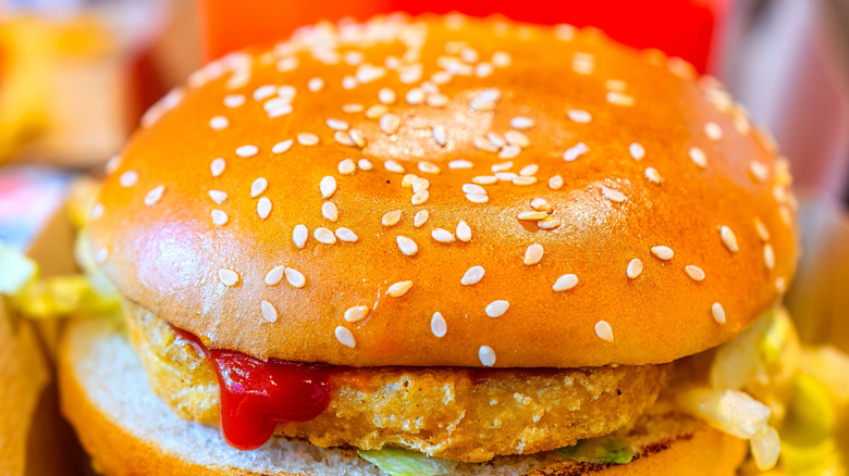 A closeup of a chicken Big Mac dripping with ketchup