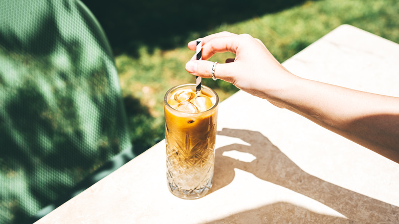 Person stirring iced coffee