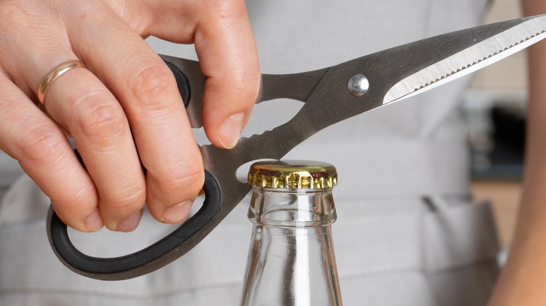 Person opening bottle with scissors