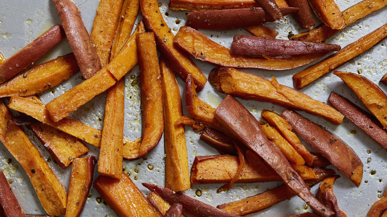 Baked sweet potato fries covered in oil on a metal pan