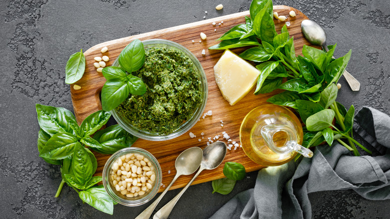 Pesto alla Genovese on wooden cutting board surrounded by ingredients