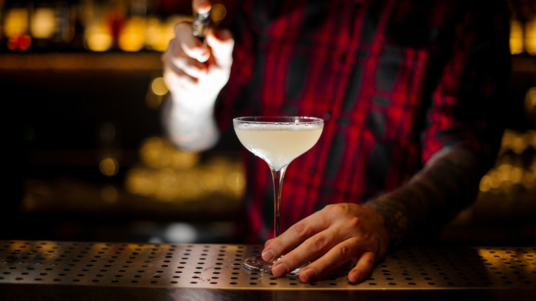 A bartender spraying a Corpse Reviver drink with absinthe