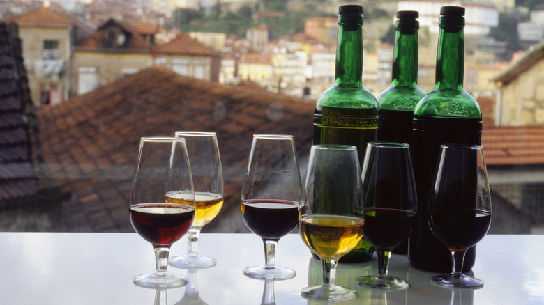 Various glasses of port wine with their respective bottles.