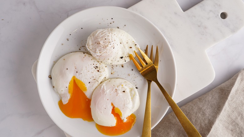 poached eggs on a plate with golden forks