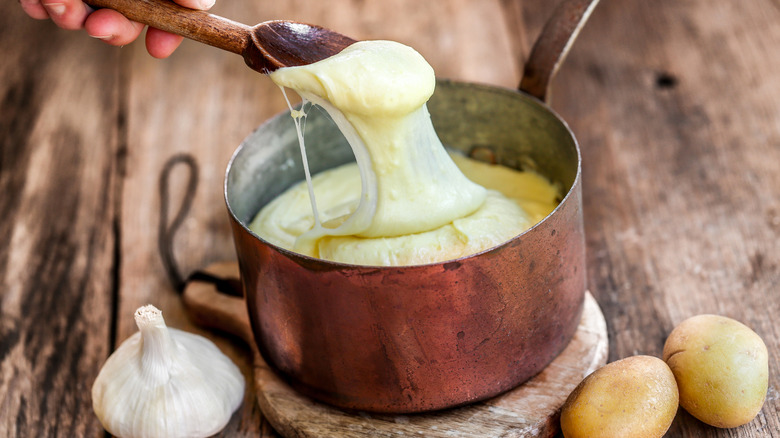 Aligot in a copper pan with garlic on the side