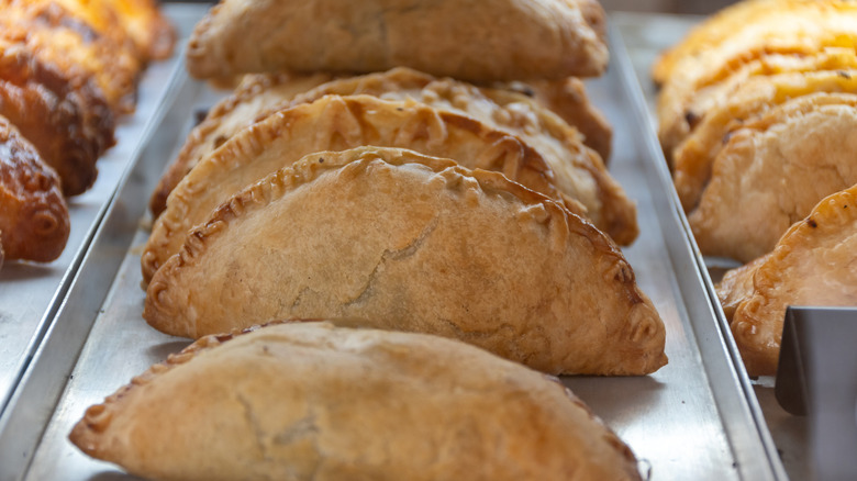 metal tray of freshly baked meat pies lined up