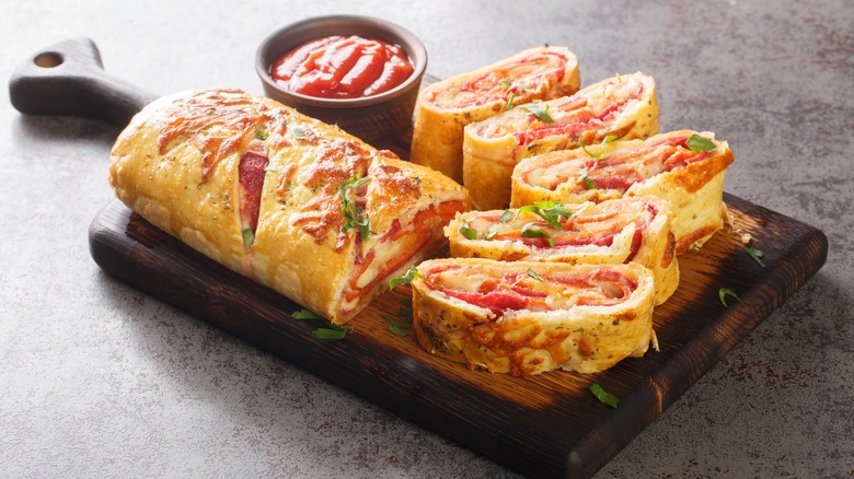 Sliced stromboli with melted cheese, salami, and marinara dipping sauce