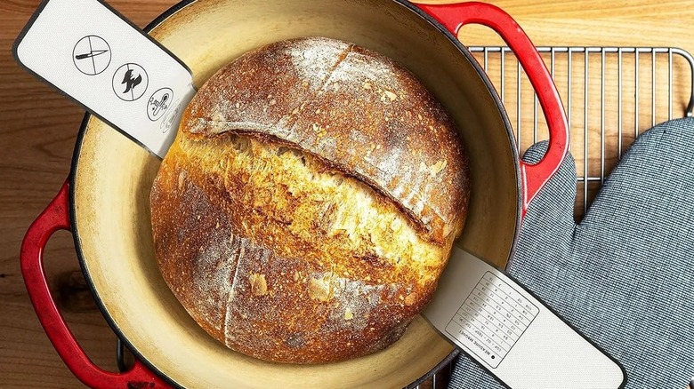 Silicone bread sling cradling baked bread in Dutch oven