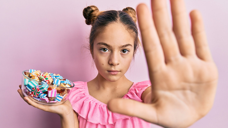 girl holding candy with hand up