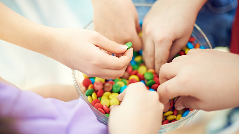children taking candy from bowl