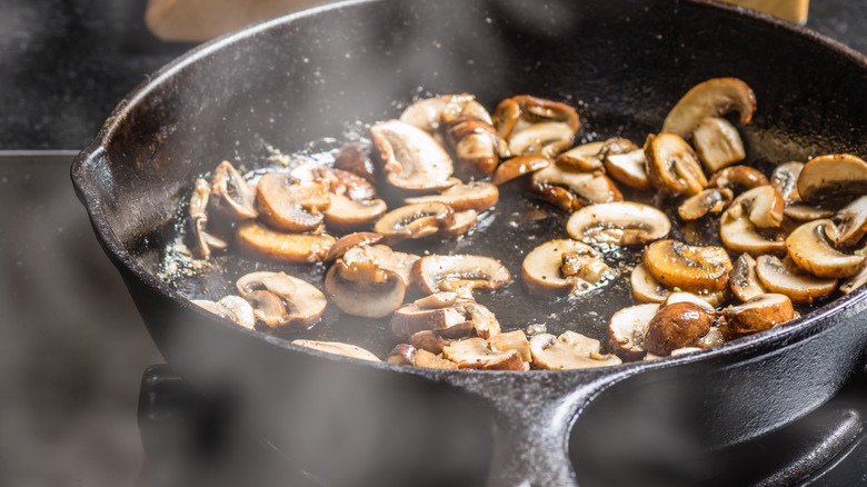 Sliced mushrooms sauteing in cast iron pan