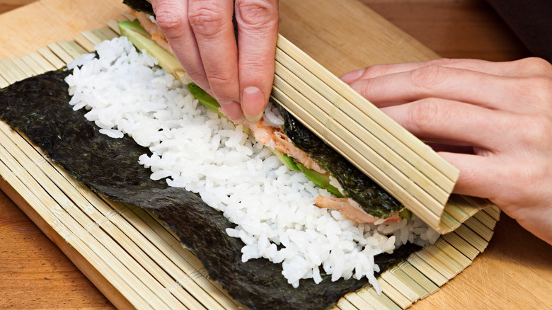 Hands rolling sushi roll