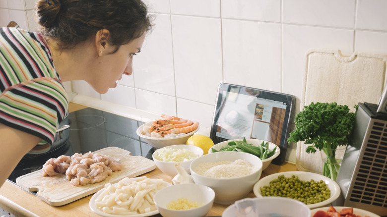 Woman reading a recipe on a tablet while she prepares mise en place