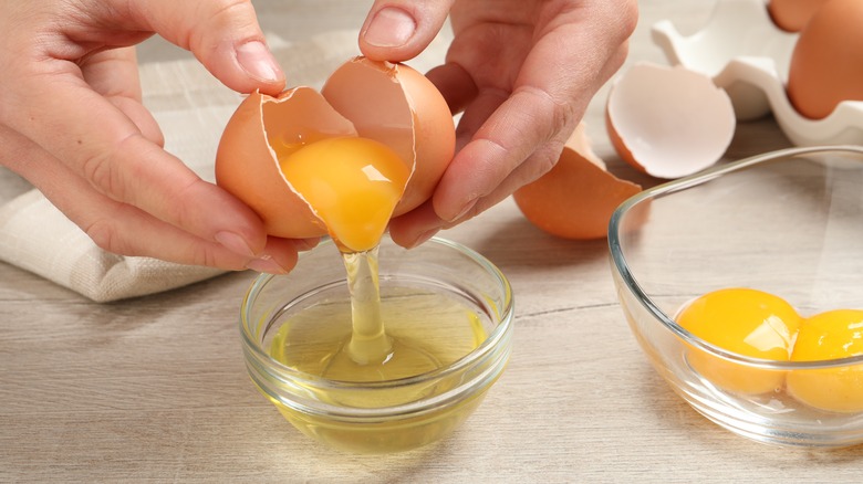 hands cracking raw egg into dish