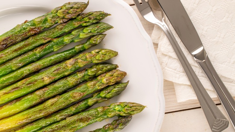 Grilled asparagus on plate with knife and fork
