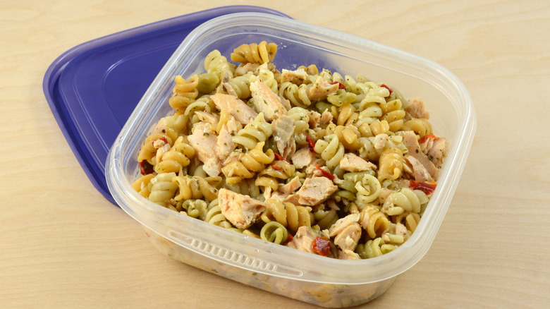 Leftover salmon pasta salad is stored in a plastic container.