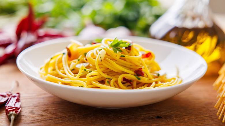 A plate of spaghetti aglio e olio with chili flakes, fresh parsley, garlic, and a drizzle of extra virgin olive oil