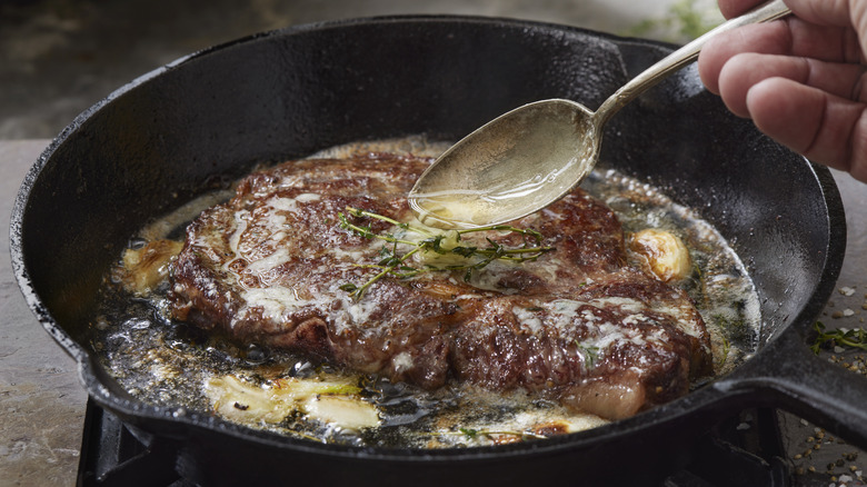 Cooking steak in hot skillet with oil or butter