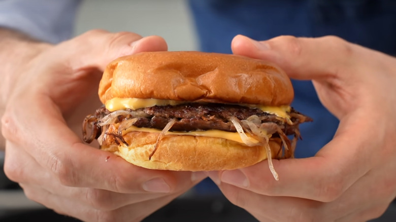 Hands holding Oklahoma onion burger