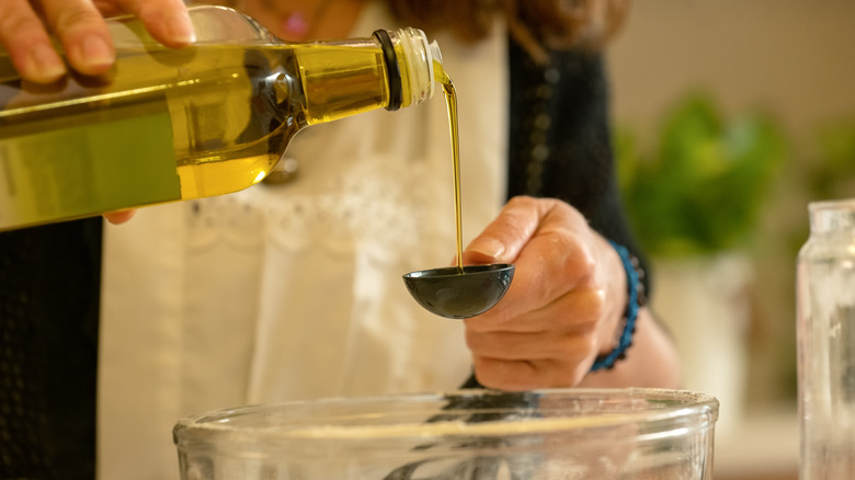Measuring olive oil into bowl