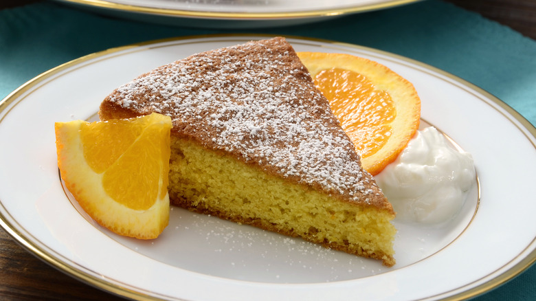 Cake with powdered sugar on top next to fruit wedges