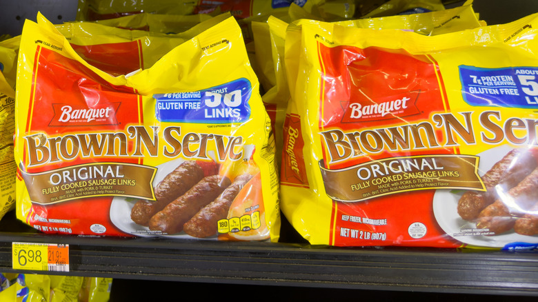 Bags of Banquet Brown N' Serve sausage links in the freezer section of a grocery store