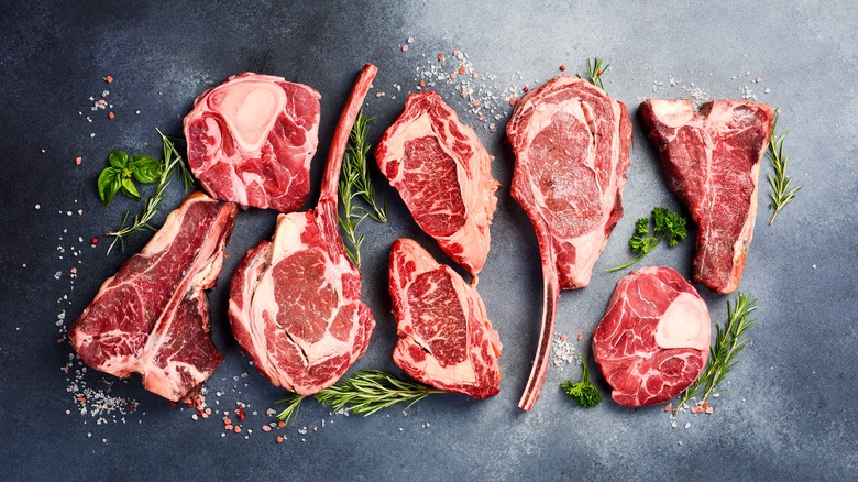 Different cuts of raw steak with salt and herbs