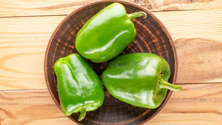 Two green bell peppers on white background