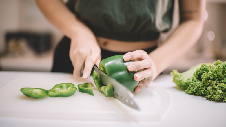 Woman chopping a green bell pepper