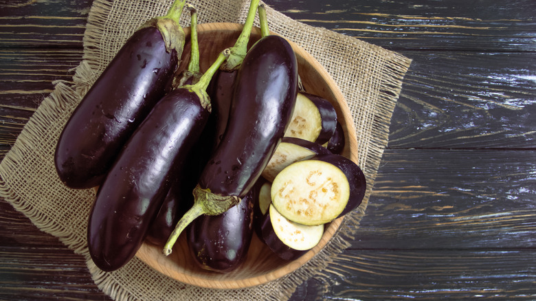 A bowl full of eggplants and eggplant pieces on a table