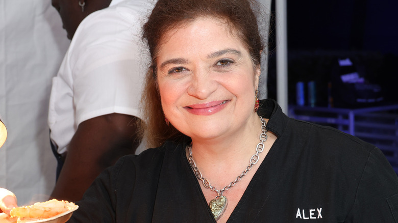 Alex Guarnaschelli smiling while eating shrimp 