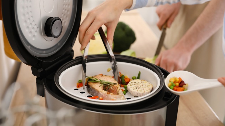 People cooking fish and veggies in a steamer