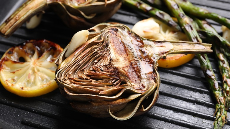 Half of a grilled artichoke on black grill pan