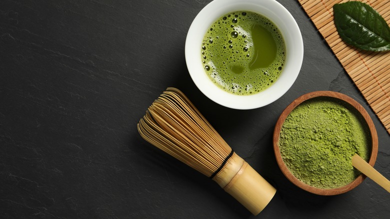 A chasen next to a bowl of matcha