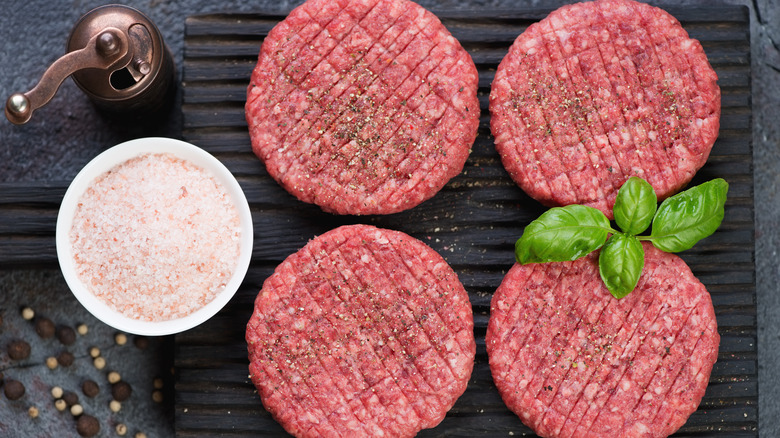 Raw burger patties with salt and pepper to season