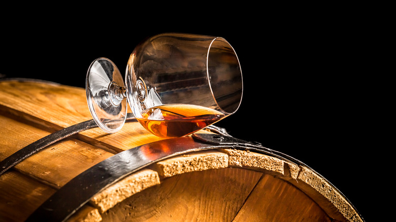 Glass of Cognac tipped over on a vintage barrel