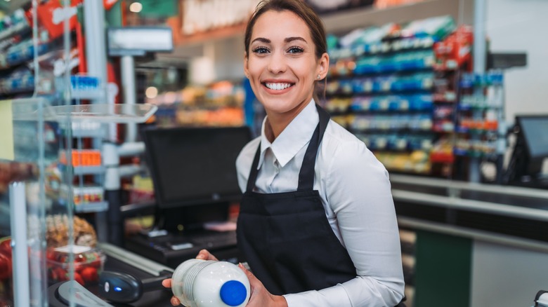 A smiling female employee scans groceries in a supermarket